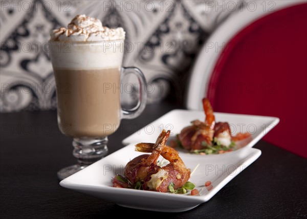 Shrimps with bacon on plates and cocktail in glass