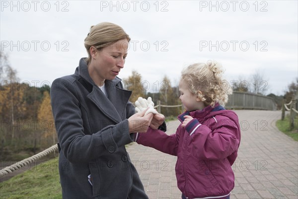 Mother putting glove on daughter's hand (4-5)