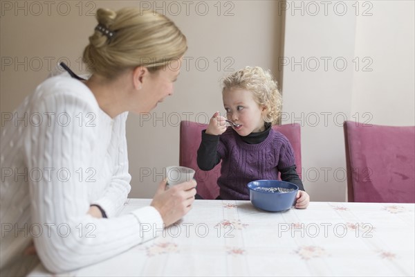 Mother looking at daughter (4-5) eating breakfast