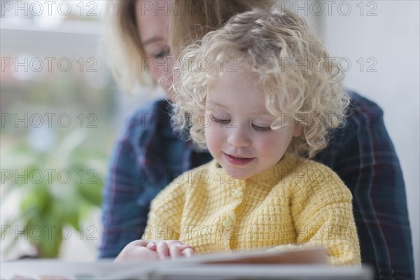 Mother reading book to daughter (4-5)