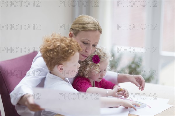 Mother looking at drawings with son (8-9) and daughter (4-5)