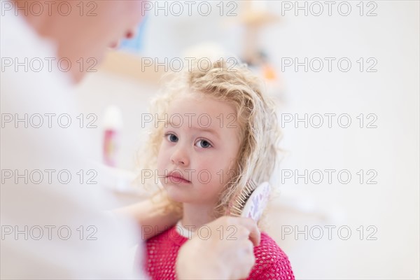 Mother brushing daughter's (4-5) hair