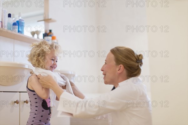 Mother helping daughter (4-5) get dressed