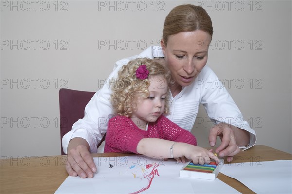 Mother and daughter (4-5) drawing with crayons