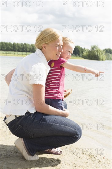 Mother and daughter (4-5) looking at view by lake