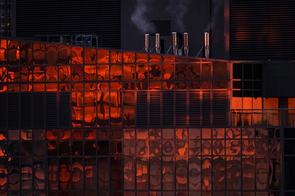 USA, New York State, New York City, Reflection on glass facade of office building at sunset.