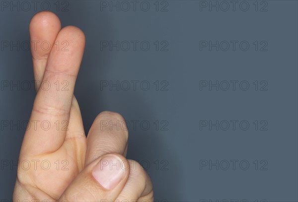 Close-up of hand with fingers crossed.