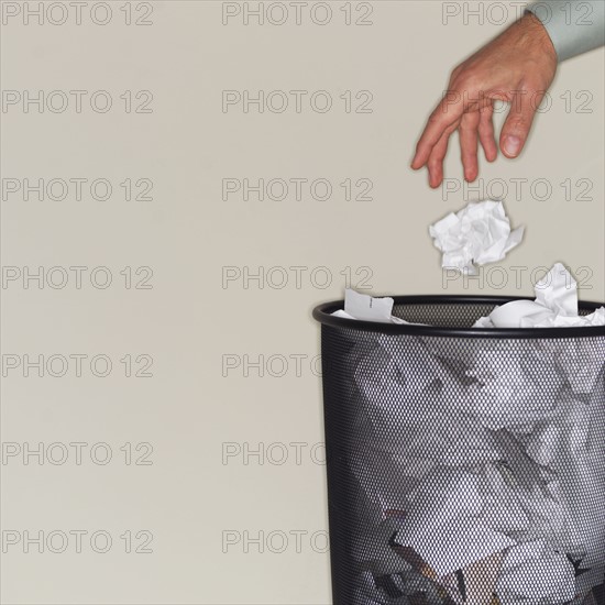 Man throwing paper balls into wastepaper basket.