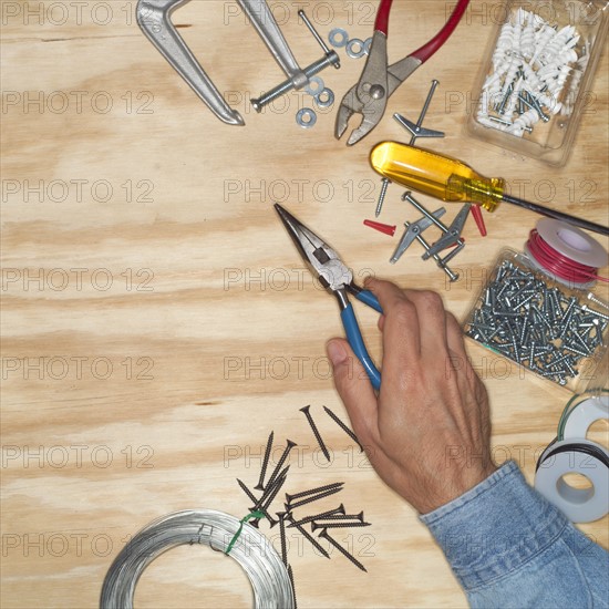 Hand of man holding pliers in workshop.