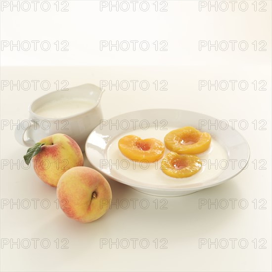 Halved peaches in bowl of cream.