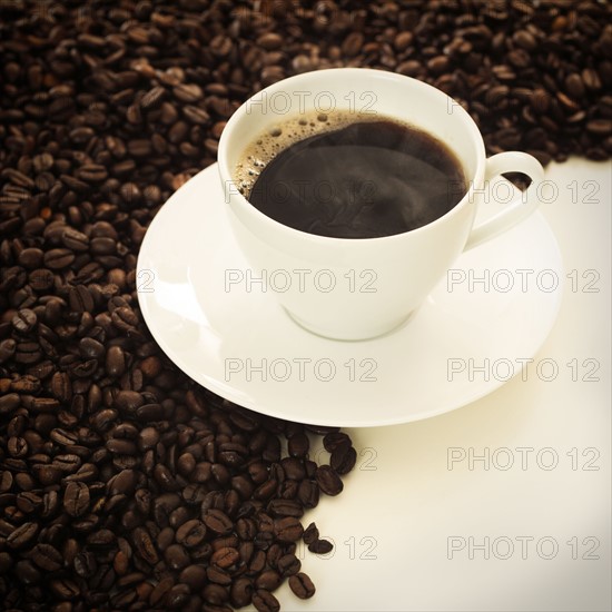 Cup of coffee among coffee beans.