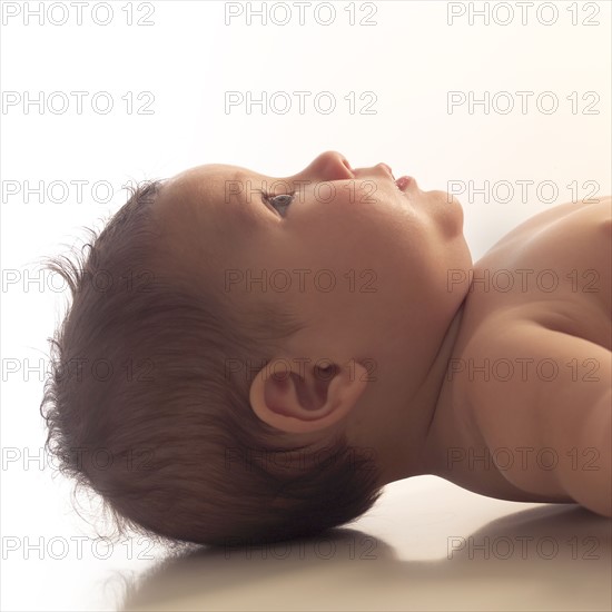 Profile portrait of baby girl (6-11 months) lying down.