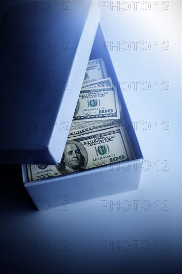 100 dollar bills in blue cardboard box.