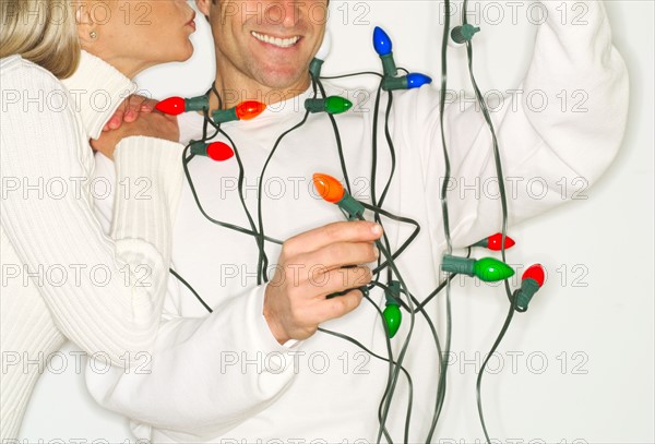 Mature couple wrapped in christmas lights.