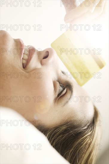 Portrait of smiling mid adult woman lying down and looking at credit card.