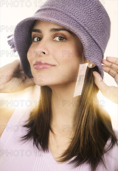 Portrait of mid adult woman trying on knitted hat.