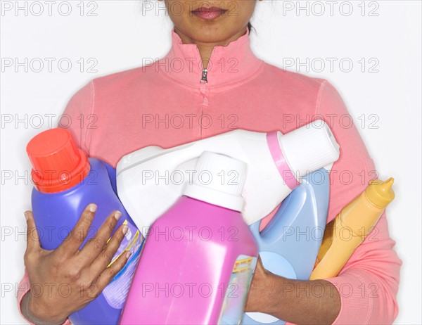 Detergent bottles held by mid adult woman.