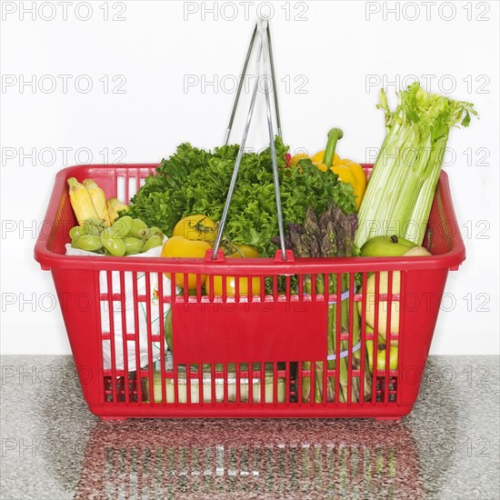 Fruits and vegetables in grocery basket on countertop.