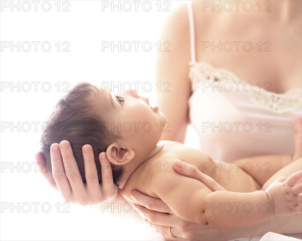 Baby girl (6-11 months) held by mid-adult woman.