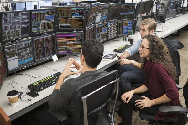 Group of young people analyzing stock market data at trading desk.