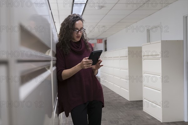 Young woman using digital tablet in corridor.