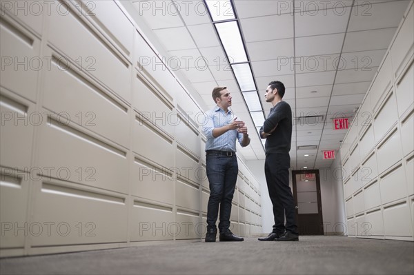 Young men talking to each other in corridor.