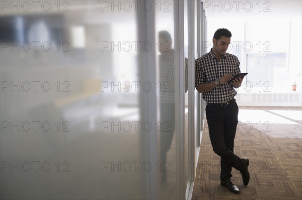 Young man standing in corridor with digital tablet.