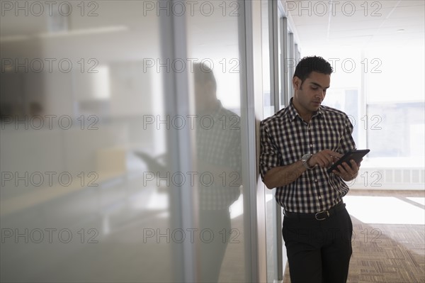 Young man standing in corridor with digital tablet.