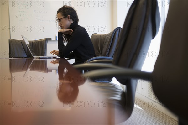 Young business woman sitting in conference room with laptop.