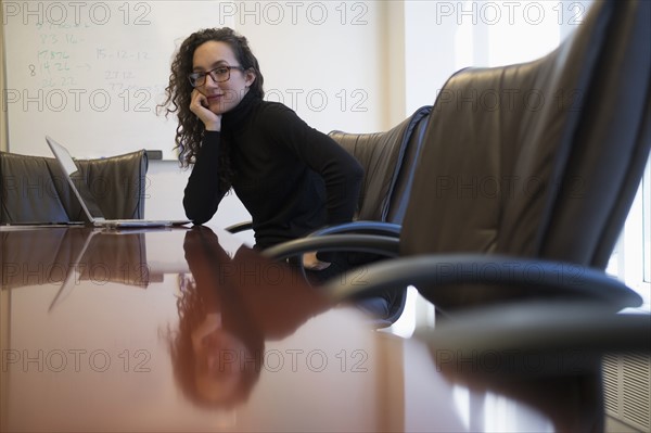 Portrait of young business woman sitting in conference room with laptop.