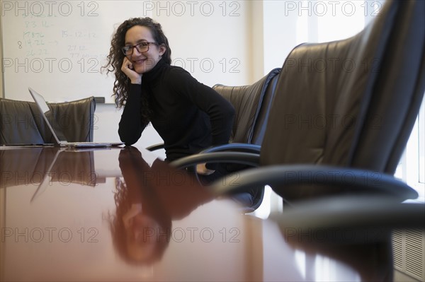 Portrait of young business woman sitting in conference room with laptop.