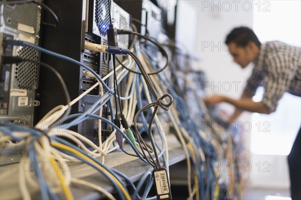 Tangled cables with young technician man in background.