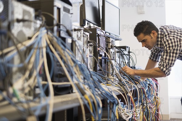 Tangled cables with young technician man in background.