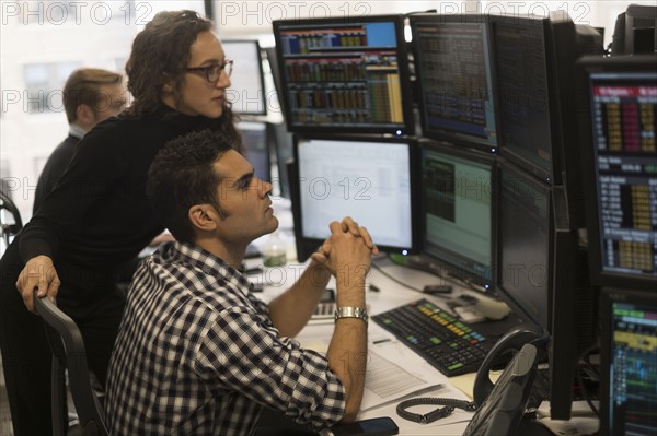 Young traders analyzing computer data.