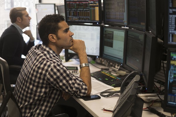 Young traders analyzing computer data.