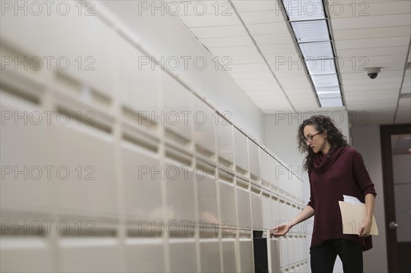 Young woman opening drawer in corridor.