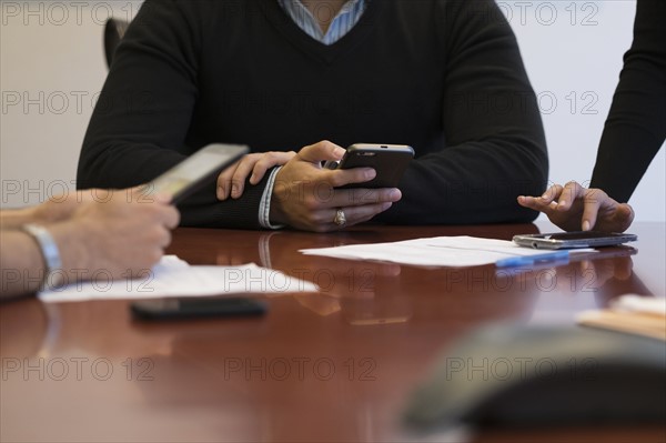 Mid section of business people using mobile phone.