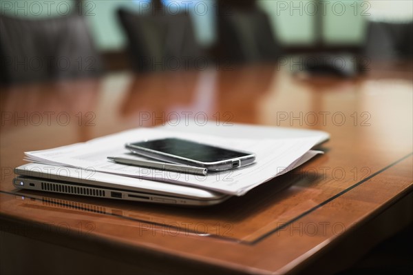 Empty conference table with mobile devices and documents.