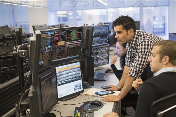 Young traders analyzing computer data.