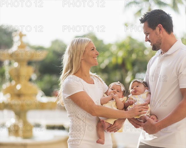 Happy family with two baby girls (2-5 months) at park