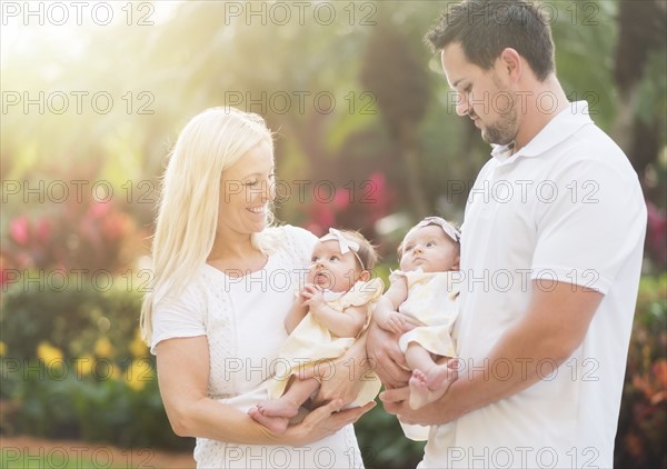 Happy family with two baby girls (2-5 months) at park