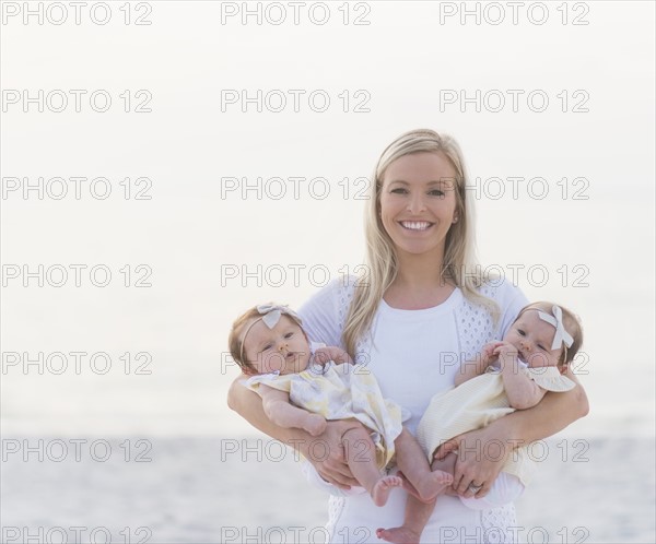 Portrait of happy mid adult mother carrying two baby girls (2-5 months)