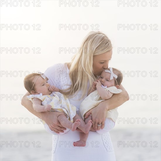 Happy mid adult mother kissing one of baby girls (2-5 months)