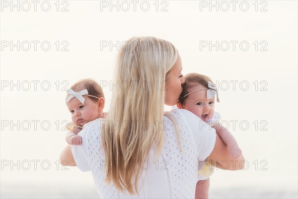 Happy mid adult mother kissing one of baby girls (2-5 months)