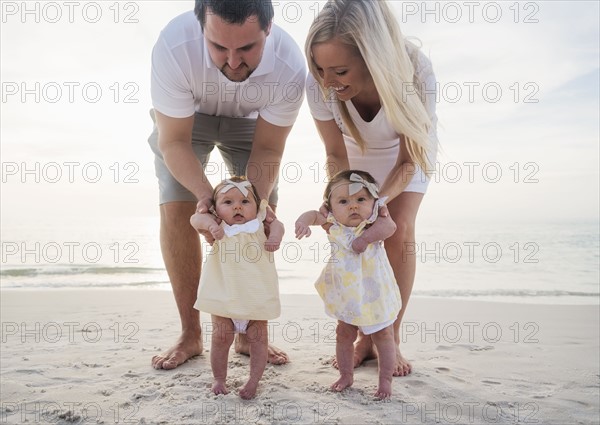 Happy family with two baby girls (2-5 months) at beach