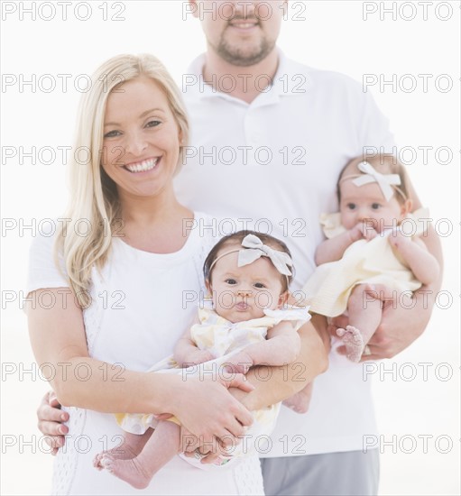 Studio shot portrait of happy family with two baby girls (2-5 months) on white background