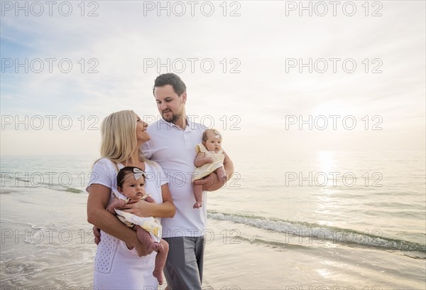 Couple with twins (2-5 months) walking along seashore