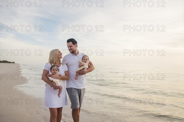Couple with twins (2-5 months) walking along seashore