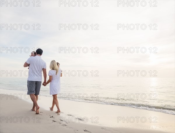 Couple with twins (2-5 months) walking along seashore