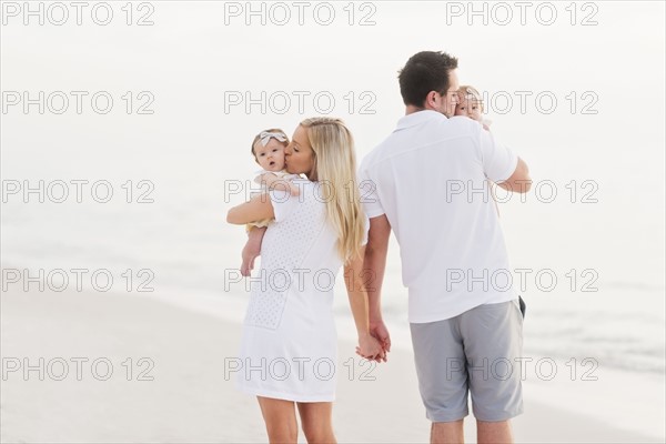 Parents walking with babies (2-5 months) along seashore